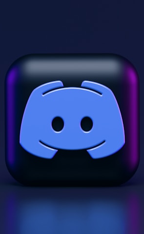 A 3D-style block with a blue logo in the center, set against a dark background. The logo resembles a game controller with two rounded edges and two circles on the front. The block has a subtle gradient, transitioning from dark to purple on its sides.